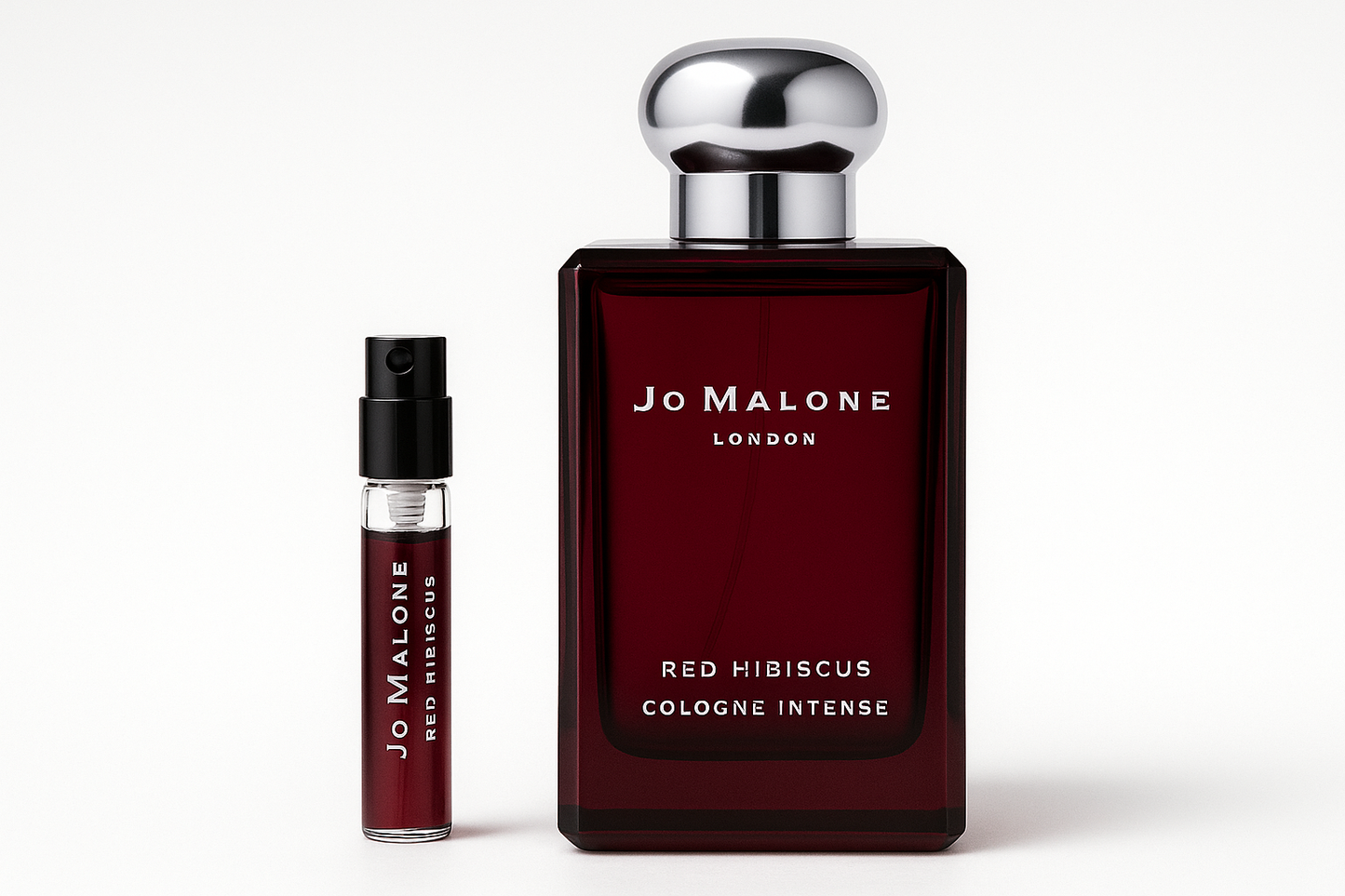 Jo Malone Red Hibiscus Cologne Intense 2 ml staaltje standing next to 100 ml perfume bottle of Jo Malone Red Hibiscus Cologne Intense which has white writing on dark red bottle