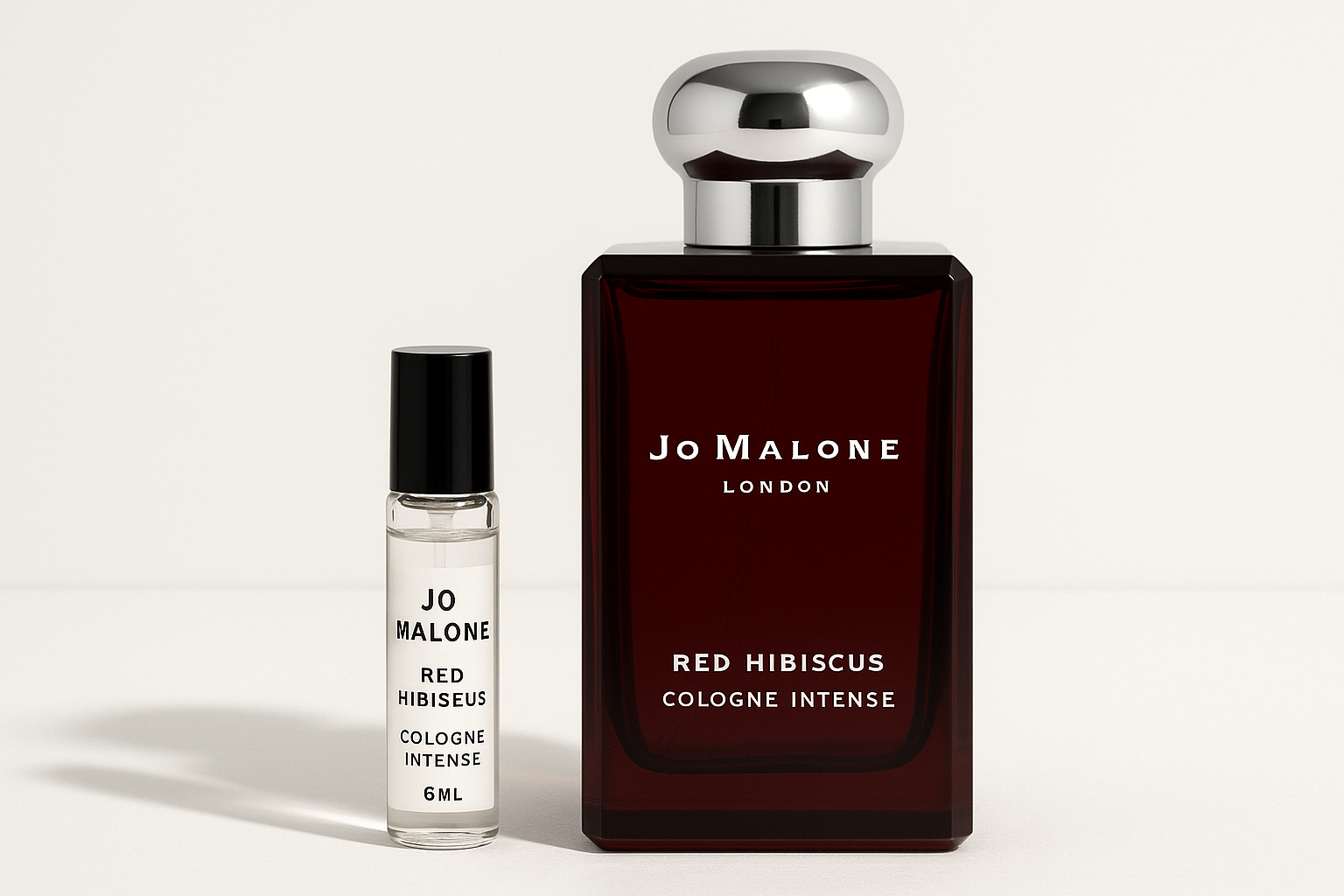 Jo Malone Red Hibiscus Cologne Intense 6 ml staaltje standing next to 100 ml perfume bottle of Jo Malone Red Hibiscus Cologne Intense which has white writing on dark red bottle